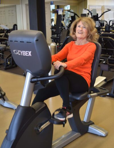 Resident smiles while using CYBEX stationary bike.