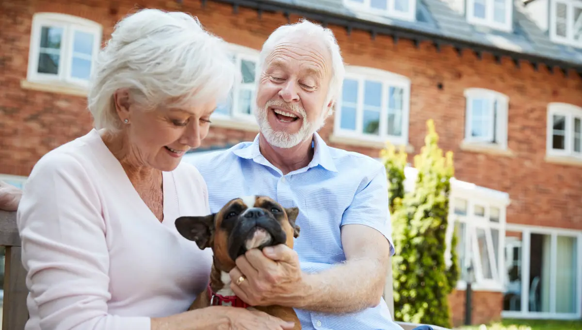 Retirees with their pet outside a red brick building Retirees with pets at retirement community