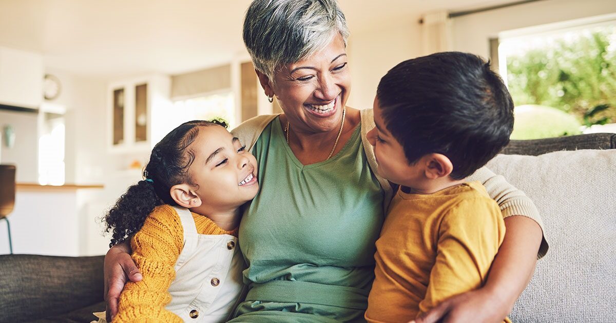 d9b9be8f-9f6b-42d4-a1f9-51c956ae0c8d Grandparent holding two grandchildren on the couch before finding something to do with them.