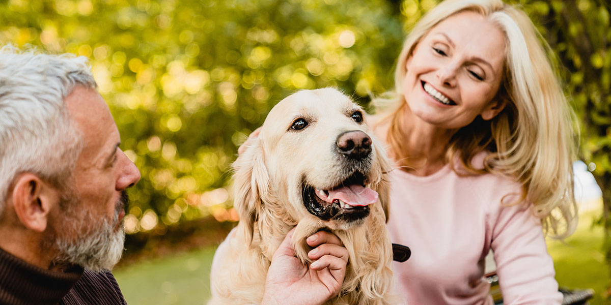 pets-in-retirement-hero Retired couple pets their dog while out for a walk in their retirement community.